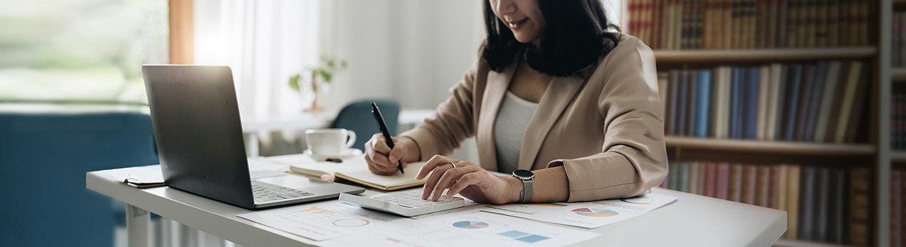 Accountant bookkeeper works on analyzing financial data using a calculator and writing notes with calculations. Accounting Concepts and Personal Financial Planning.