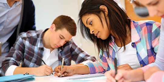 Group of teenagers in class writing an exam